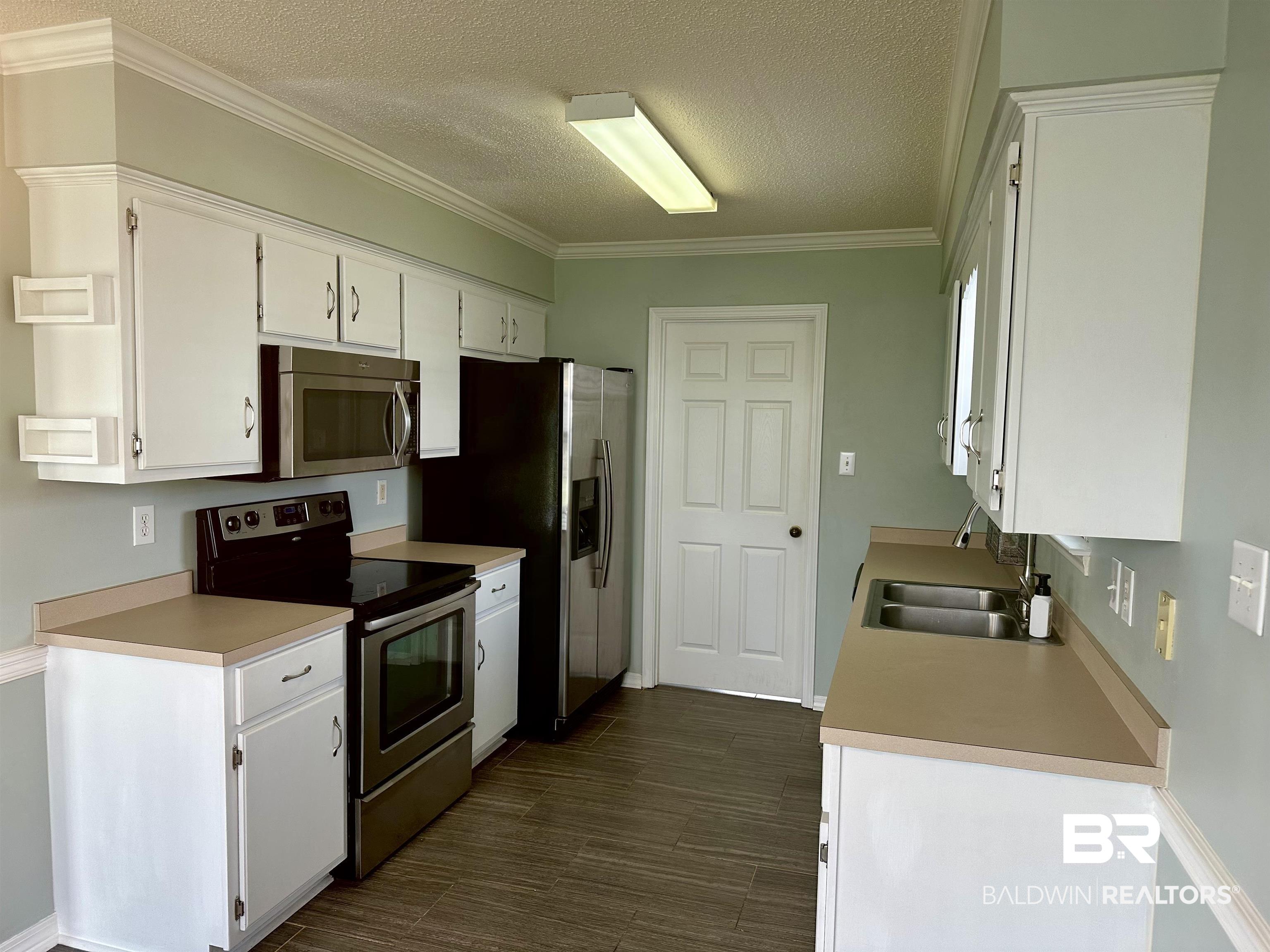 4882 Rebecca Place Mobile, AL 36695 - Photo 26 of 29 Kitchen with dark wood finished floors, a sink, light countertops, appliances with stainless steel finishes, and white cabinetry