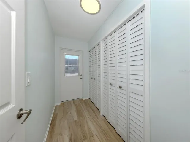 a view of a hallway with wooden floor and closet