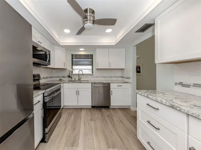 a kitchen with granite countertop a sink cabinets stainless steel appliances and a counter space