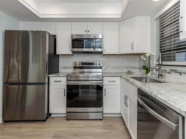a kitchen with cabinets stainless steel appliances and wooden floor