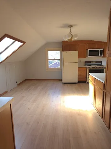 an empty room with a kitchen and a fireplace
