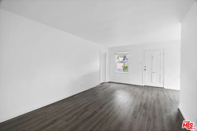 an empty room with wooden floor and white walls
