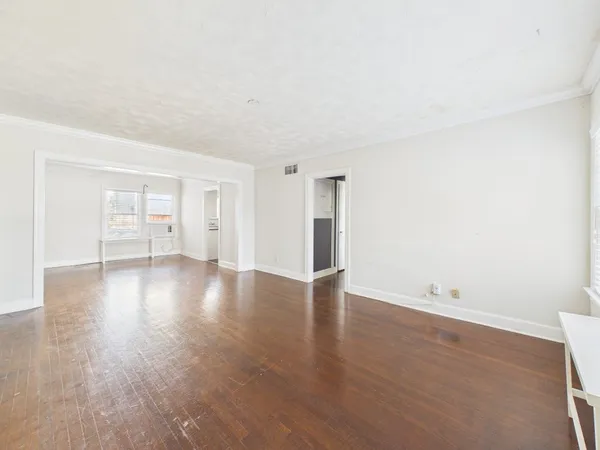 a view of an empty room with wooden floor and a window