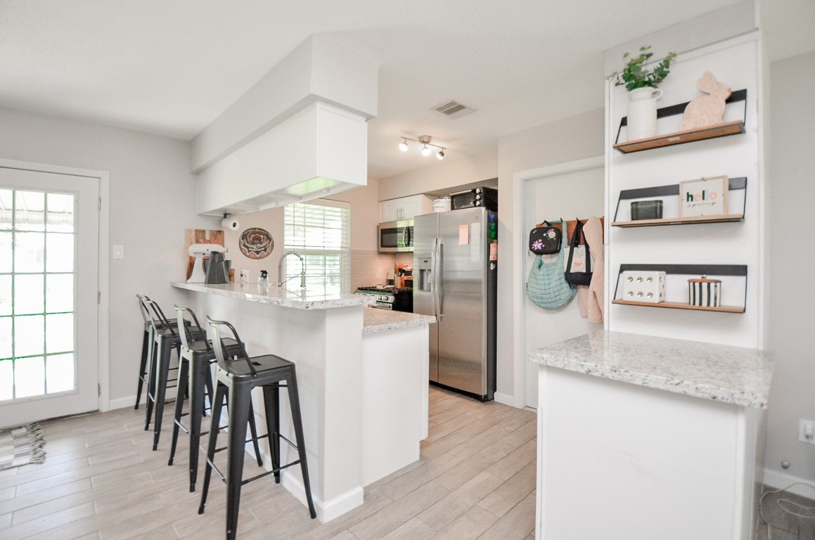 201 Inwood Lane Highlands, TX 77562 - Photo 12 of 31 a kitchen with stainless steel appliances granite countertop a refrigerator a stove and white cabinets with wooden floor