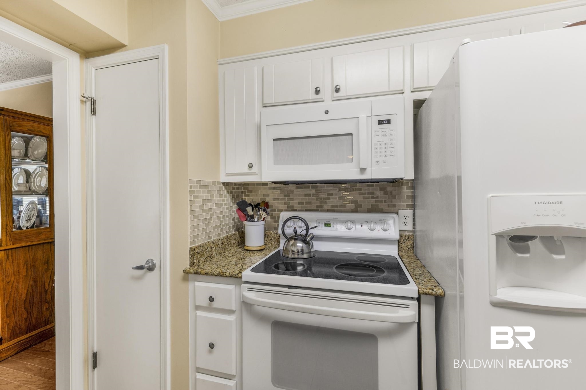 10207 Plantation Drive Daphne, AL 36526 - Photo 37 of 48 Kitchen featuring white appliances, white cabinetry, dark stone countertops, crown molding, and tasteful backsplash