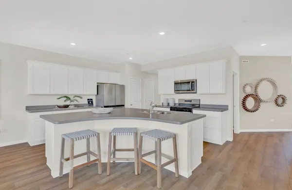 a kitchen with stainless steel appliances granite countertop a stove top oven a sink dishwasher and a refrigerator with wooden floor