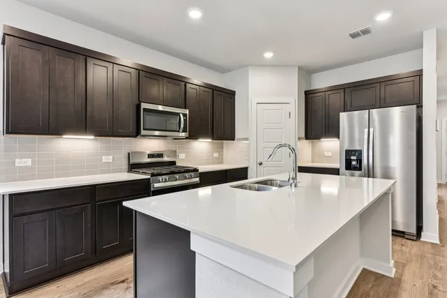 a kitchen with stainless steel appliances a refrigerator stove microwave sink and cabinets