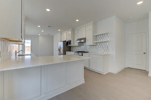a kitchen with white cabinets and appliances