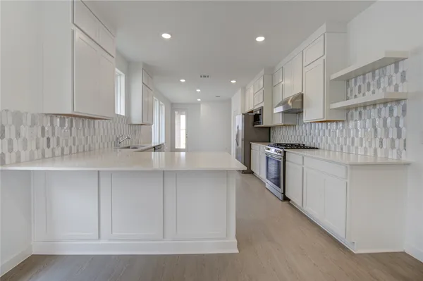 a kitchen with stainless steel appliances granite countertop a sink a stove and a refrigerator