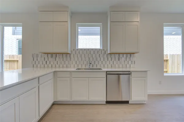 a kitchen with white cabinets appliances a sink and a window
