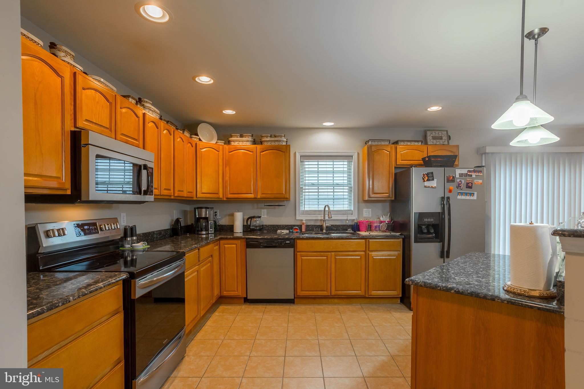 10455 Sunnyside Road Greenwood, DE 19950 - Photo 14 of 46 a kitchen with stainless steel appliances granite countertop a sink a stove top oven a counter space and cabinets