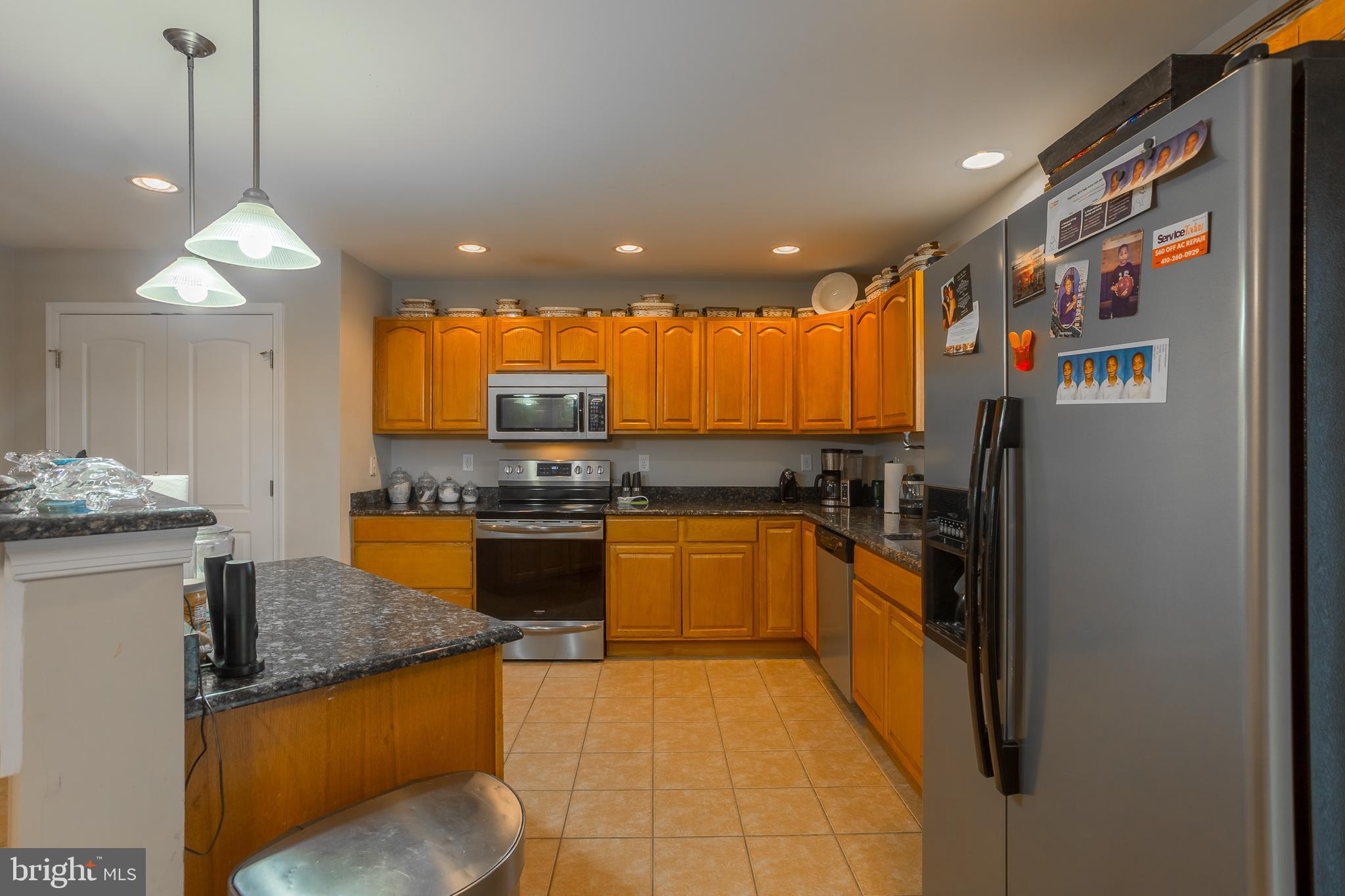 10455 Sunnyside Road Greenwood, DE 19950 - Photo 15 of 46 a kitchen with stainless steel appliances granite countertop a refrigerator a sink dishwasher a stove and a dining table with wooden floor