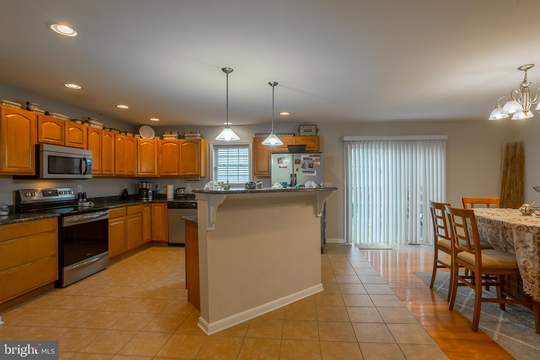 10455 Sunnyside Road Greenwood, DE 19950 - Photo 4 of 46 a kitchen with stainless steel appliances kitchen island granite countertop a stove a sink a dining table and chairs with wooden floor