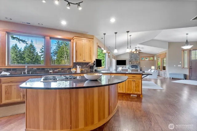 a kitchen with stainless steel appliances granite countertop a sink a large window and wooden floors