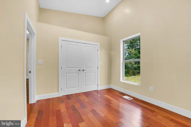 a view of empty room with wooden floor and fan