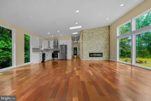 a view of an empty room with a window and kitchen view