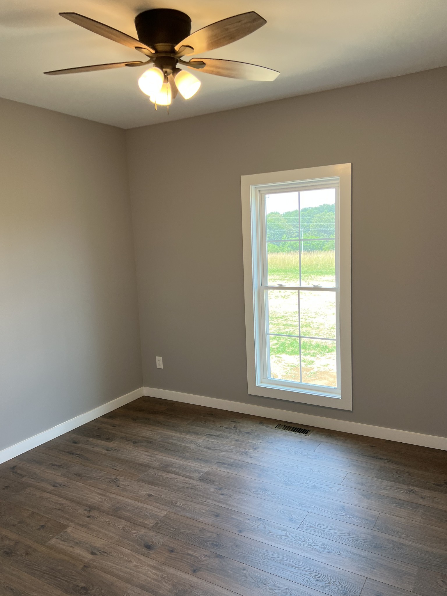 1504 Fall River Road Lawrenceburg, TN 38464 - Photo 11 of 15 an empty room with wooden floor chandelier fan and windows