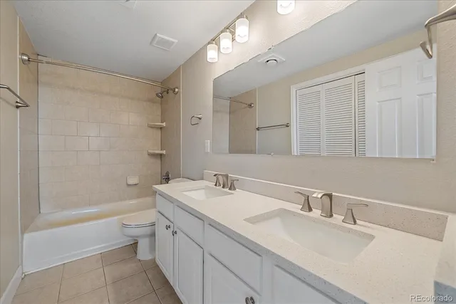 a bathroom with a double vanity sink a toilet a mirror and shower