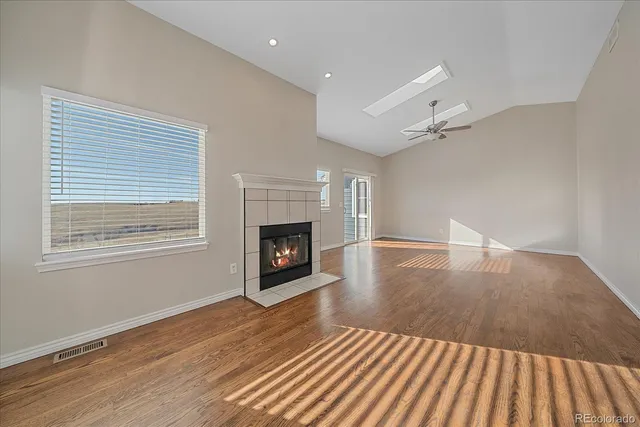 an empty room with wooden floor fireplace and windows