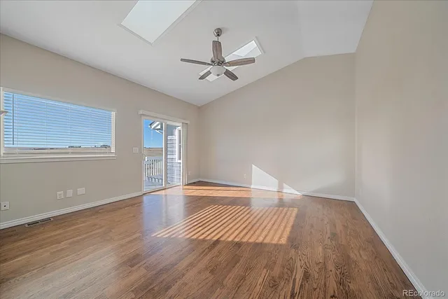 an empty room with wooden floor fan and windows