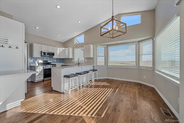 a kitchen with stainless steel appliances granite countertop a refrigerator a sink dishwasher a stove and white countertops with wooden floor