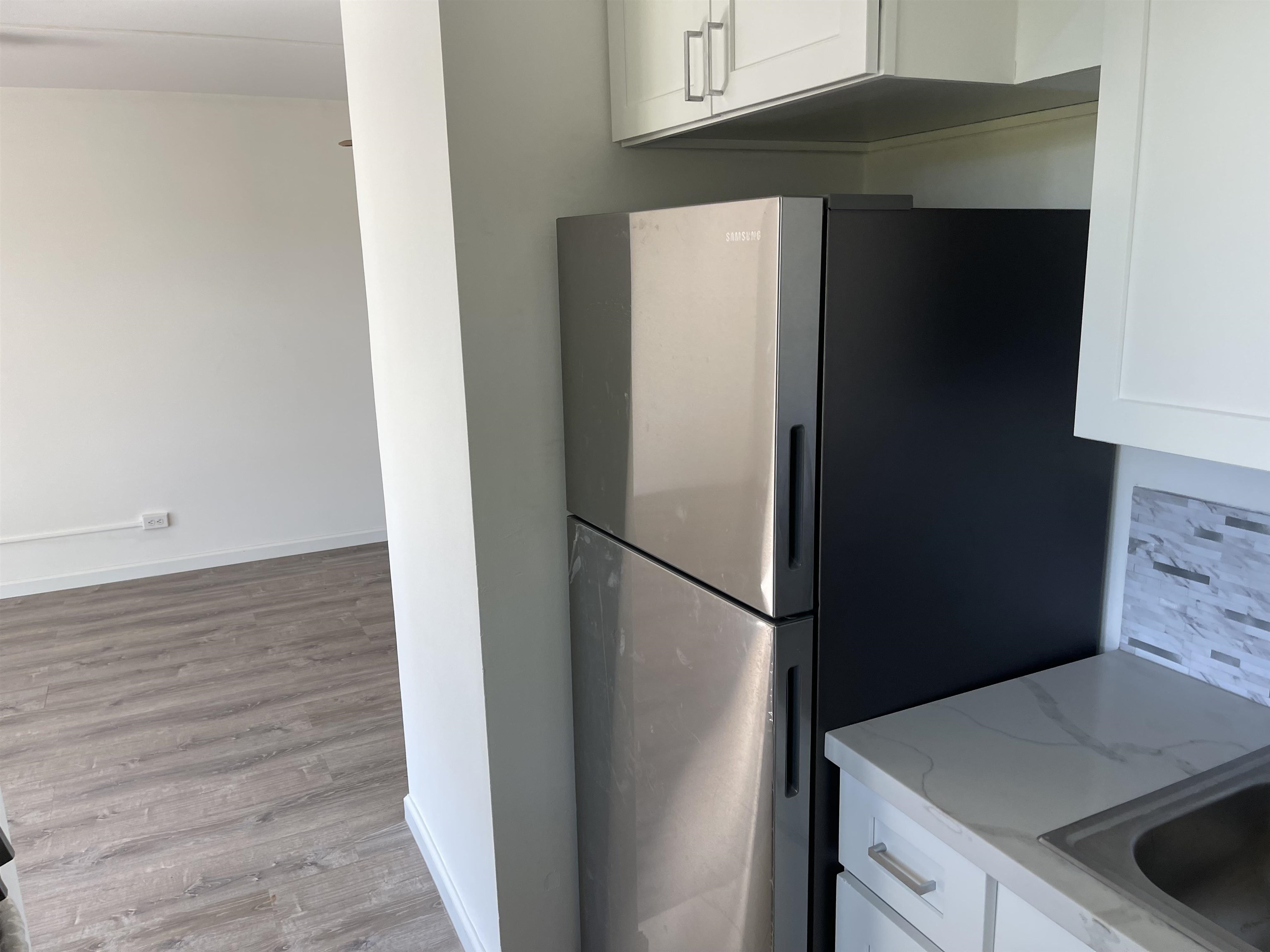 4310 Lower Honoapiilani Road, Unit 516 Lahaina, HI 96761 - Photo 3 of 16 a close view of a refrigerator in kitchen and an empty room with wooden floor