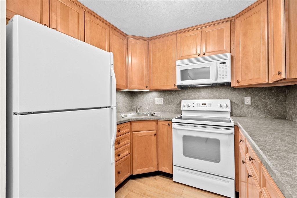 79 Fountain Lane, Unit 3 Weymouth, MA 02190 - Photo 4 of 29 a kitchen with a white cabinets and refrigerator