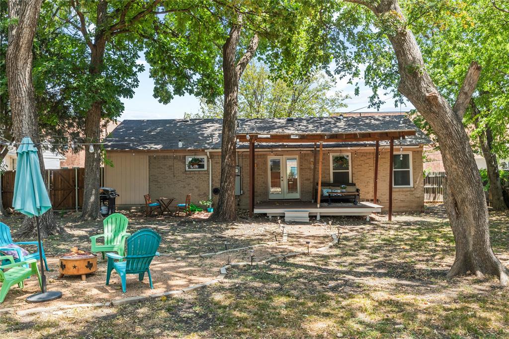 649 Peavy Road Dallas, TX 75218 - Photo 20 of 30 Brick exterior with a covered patio, multiple mature trees, and a wooden deck
