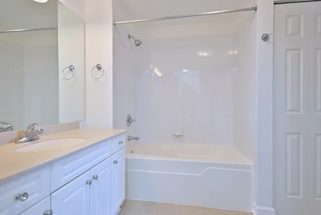 a bathroom with a bathtub shower sink vanity and mirror