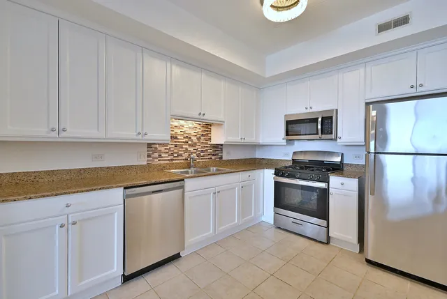 a kitchen with granite countertop white cabinets stainless steel appliances and a sink