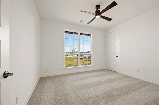 an empty room with a ceiling fan and a window