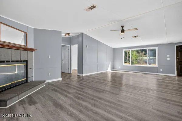 a view of an empty room with a window and wooden floor