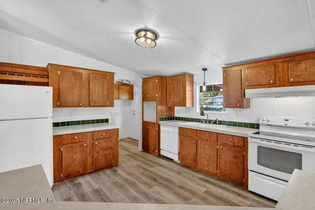 a kitchen with stainless steel appliances granite countertop a stove a refrigerator a sink dishwasher and wooden cabinets with wooden floor