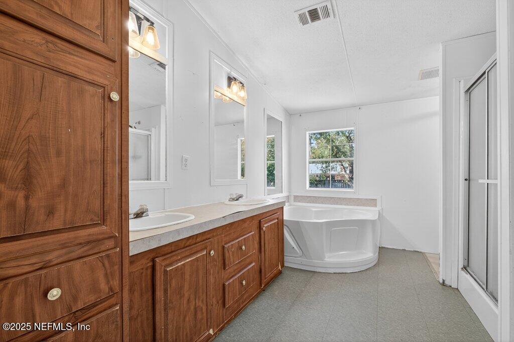 9899 Barber Loop Macclenny, FL 32063 - Photo 28 of 43 a bathroom with a granite countertop double vanity sink a mirror and a bathtub