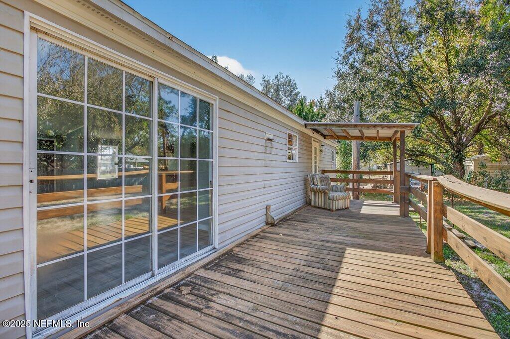 9899 Barber Loop Macclenny, FL 32063 - Photo 37 of 43 a view of a balcony with wooden floor and fence and a floor to ceiling window