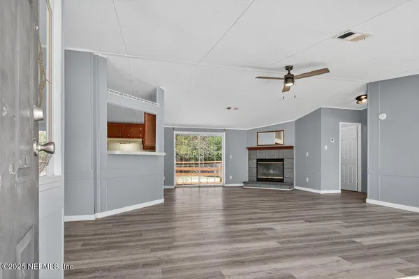 an empty room with wooden floor fireplace and windows