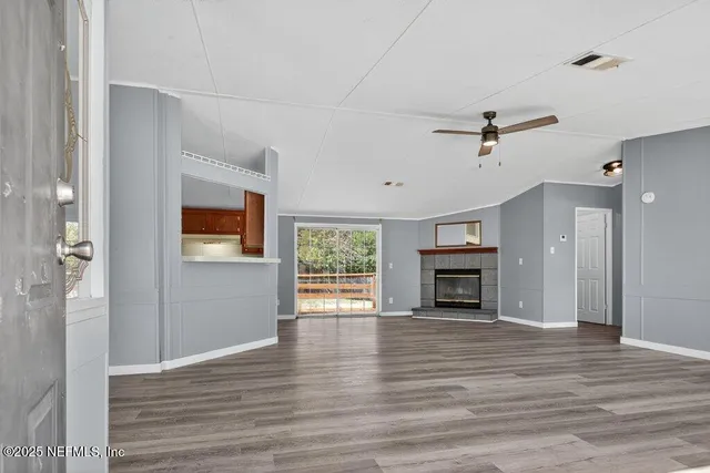 an empty room with wooden floor fireplace and windows