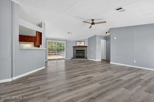 an empty room with wooden floor fireplace and windows