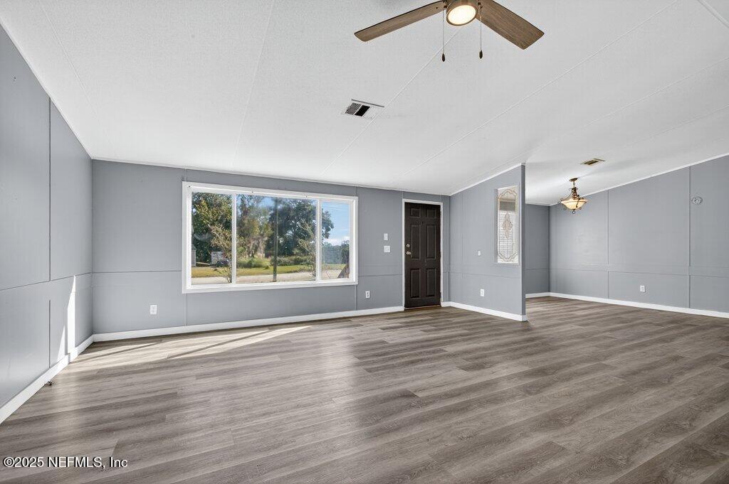 9899 Barber Loop Macclenny, FL 32063 - Photo 8 of 43 an empty room with wooden floor and windows