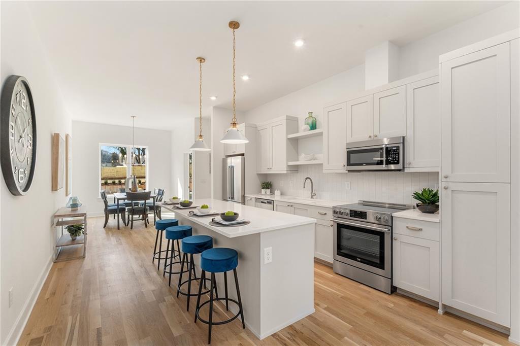 1237 Memorial Drive Southeast, Unit 403 Atlanta, GA 30316 - Photo 2 of 38 a kitchen with stainless steel appliances kitchen island granite countertop a stove a sink a oven a dining table and chairs with wooden floor