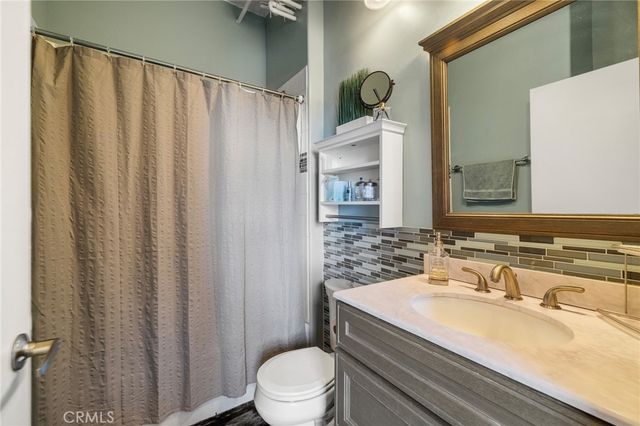 a bathroom with a granite countertop sink toilet and mirror