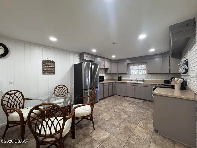a kitchen with stainless steel appliances a refrigerator a sink a stove a dining table and chairs