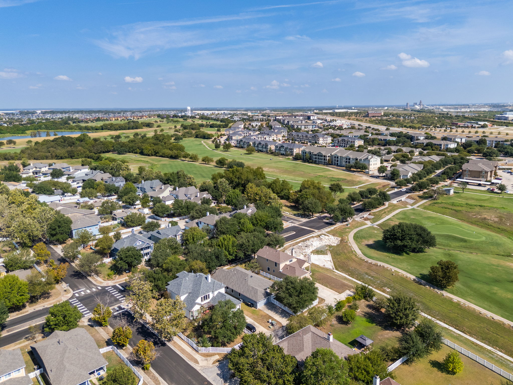 784 Sampson Kyle, TX 78640 - Photo 39 of 40 A golf course community unfolds under a blue sky, offering verdant fairways and paved streets.