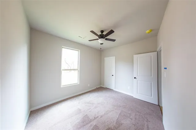 an empty room with windows and ceiling fan