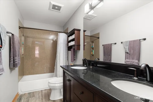 a bathroom with a double vanity sink toilet mirror and shower