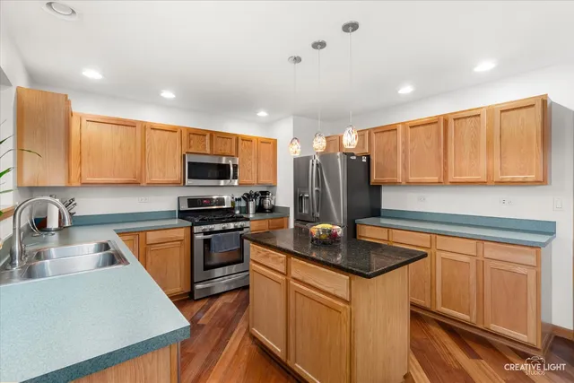 a kitchen with stainless steel appliances granite countertop a sink a stove a refrigerator a center island and cabinets