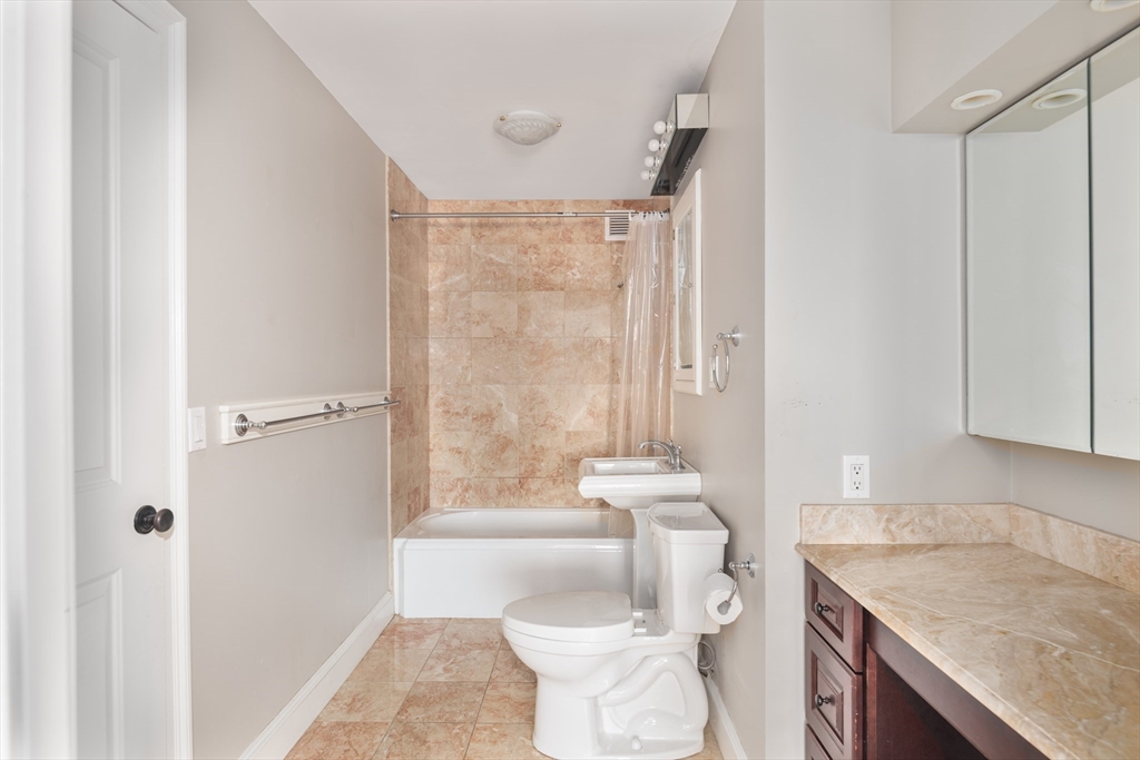 85 East India Row, Unit 15E Boston, MA 02110 - Photo 16 of 20 a bathroom with a granite countertop sink toilet and shower