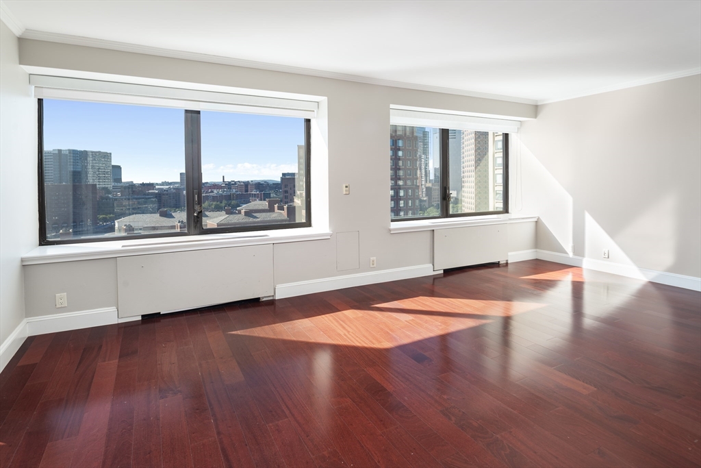 85 East India Row, Unit 15E Boston, MA 02110 - Photo 2 of 20 a view of an empty room with wooden floor and a window