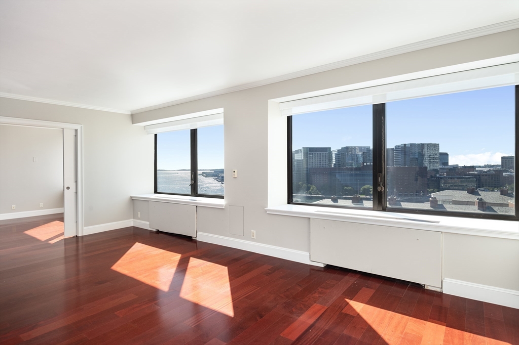 85 East India Row, Unit 15E Boston, MA 02110 - Photo 4 of 20 an empty room with wooden floor and windows