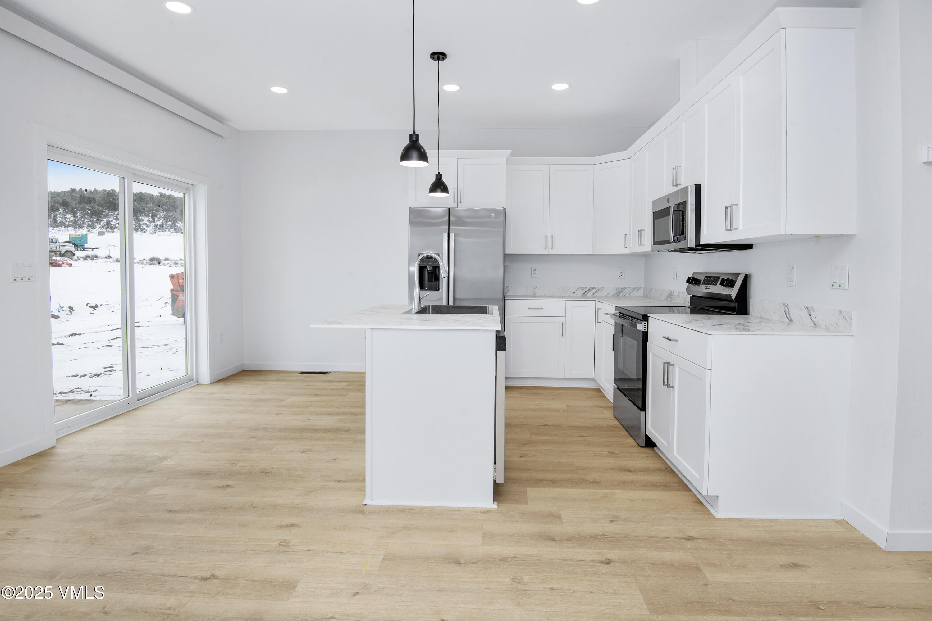 70 Comanche Way Gypsum, CO 81637 - Photo 8 of 46 a large kitchen with stainless steel appliances granite countertop a stove a sink a refrigerator and white cabinets with wooden floor